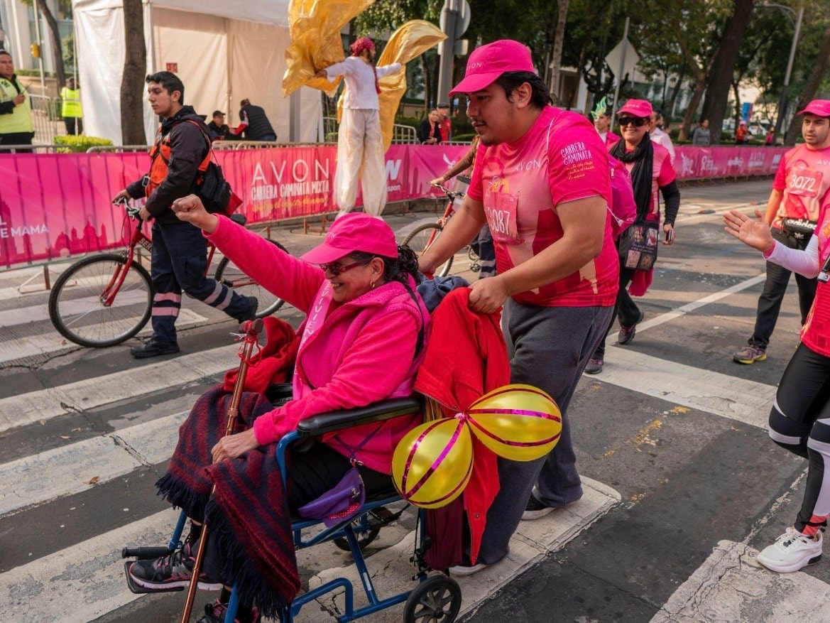 Avon Run — participante en silla de ruedas celebrando con el puño en alto en la carrera
