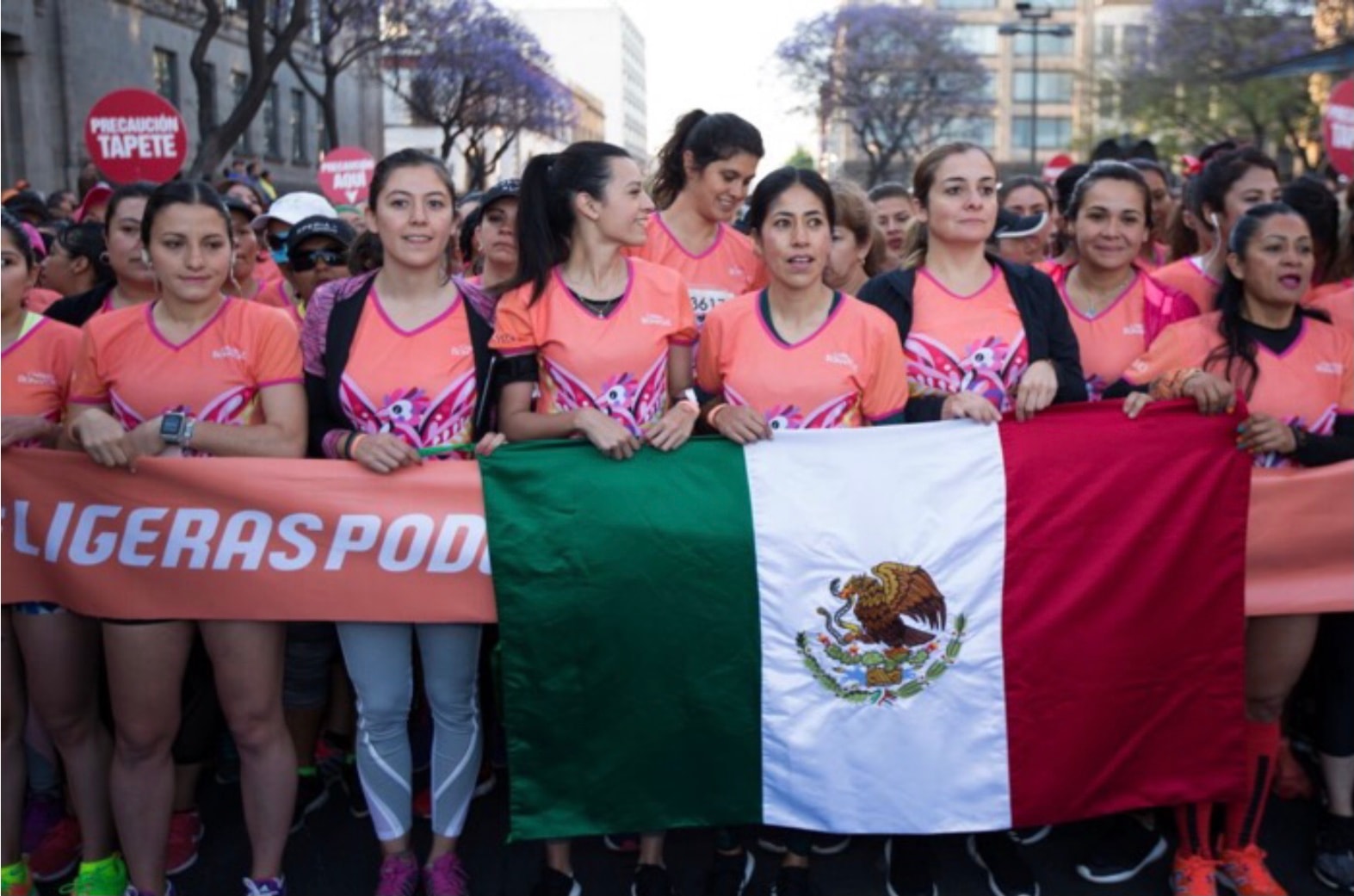 Grupo de corredoras Bonafont sosteniendo bandera mexicana en Paseo de la Reforma