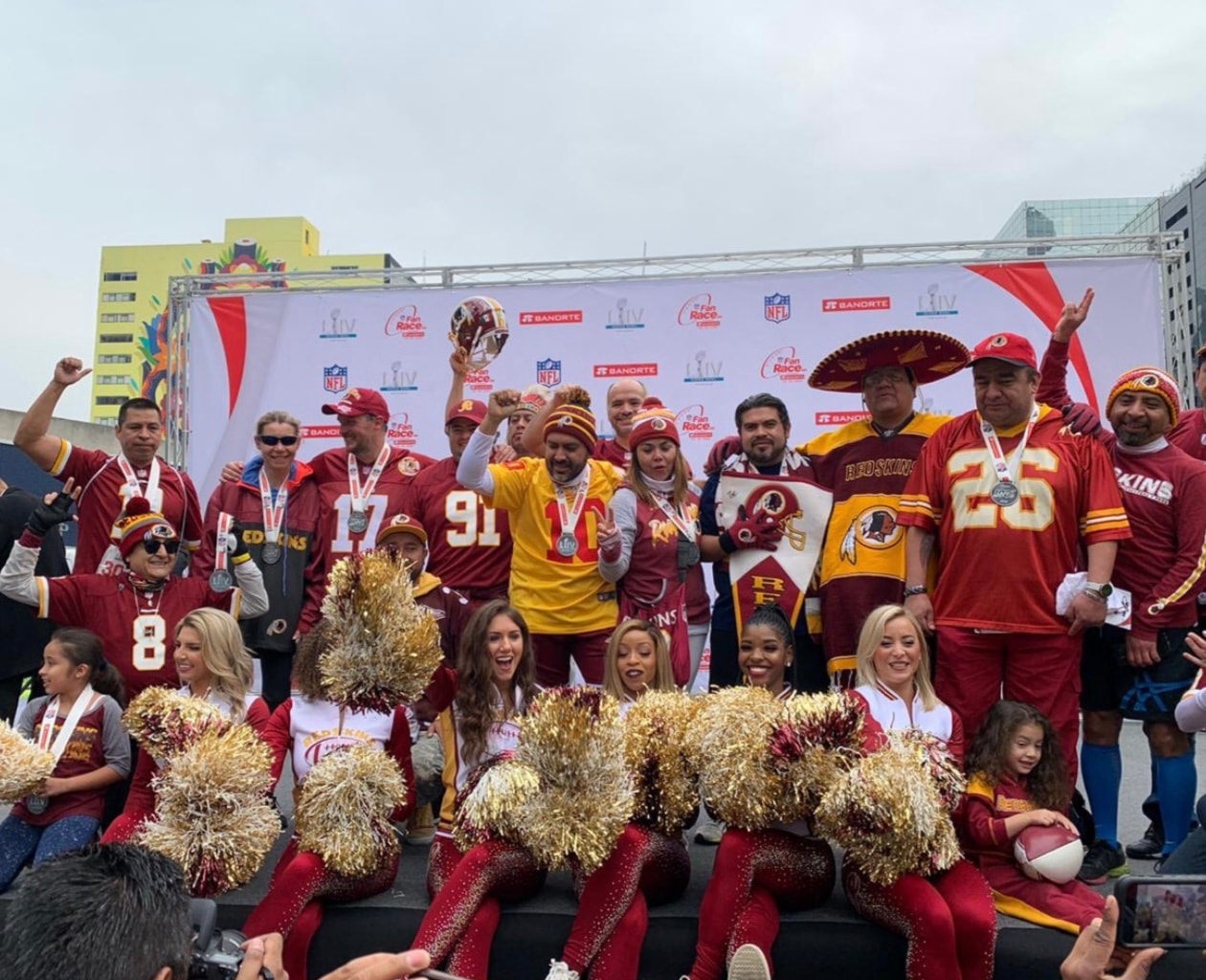Fans y cheerleaders de los Washington Commanders celebrando en el podio del NFL Fan Race