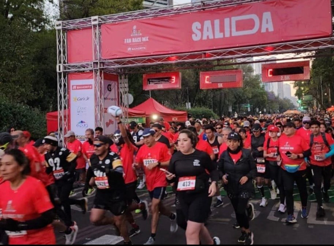 Corredores cruzando el arco de salida rojo del Fan Race MX en Paseo de la Reforma