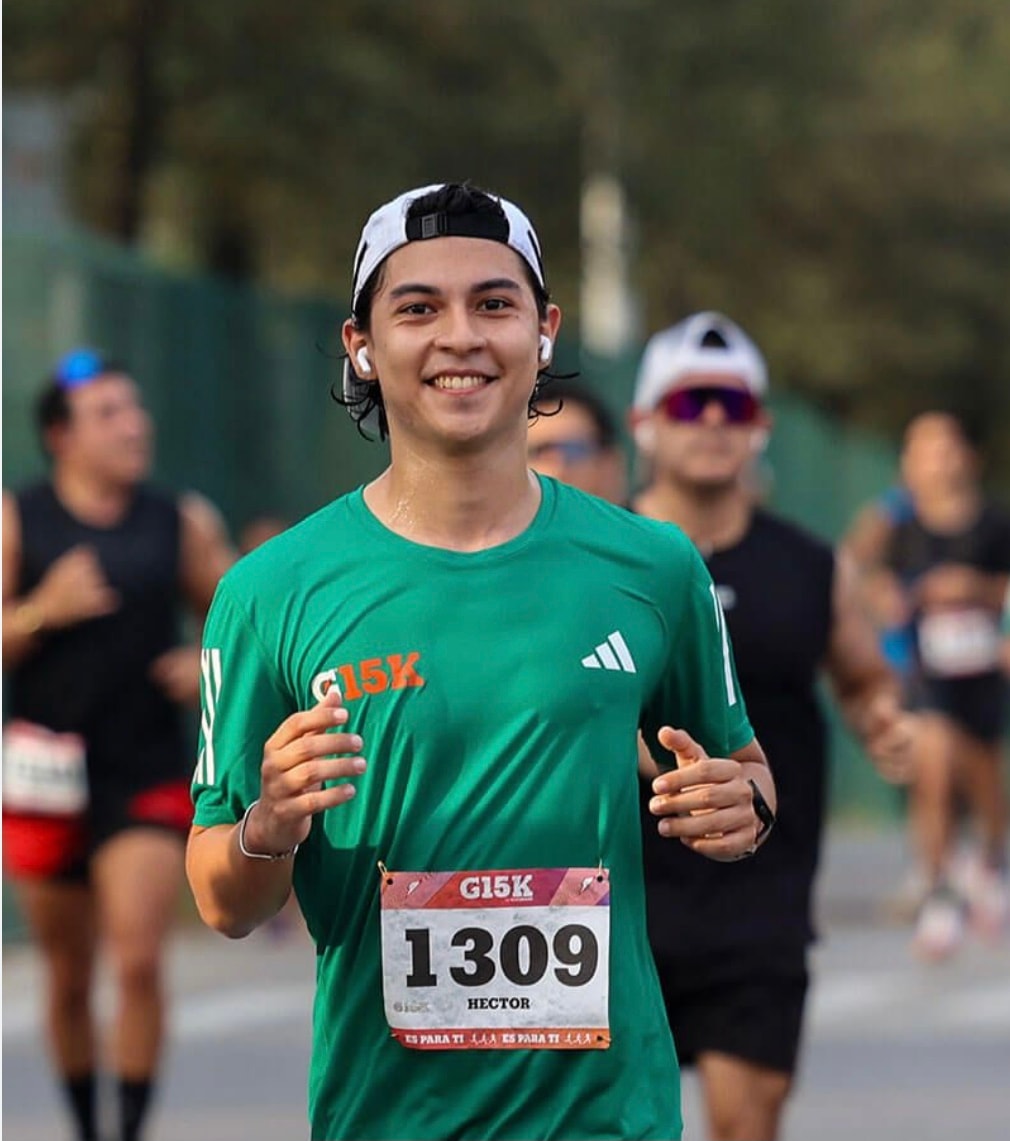 Héctor corredor #1309 con playera verde G15K sonriendo en la ruta