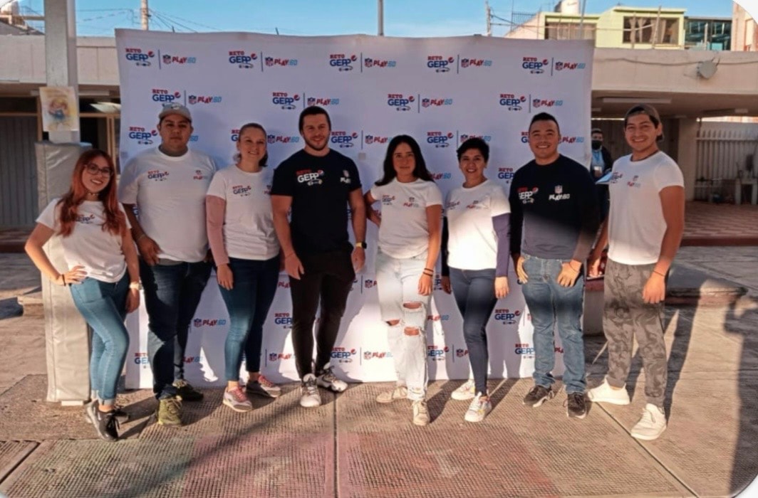 Reto Gepp — equipo de staff posando frente al backdrop oficial del evento