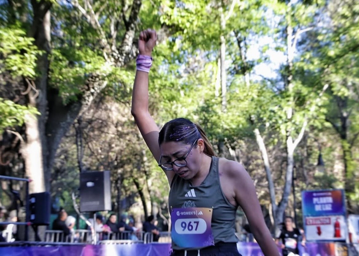 G-Women's Race — corredora cruzando la meta con el puño en alto
