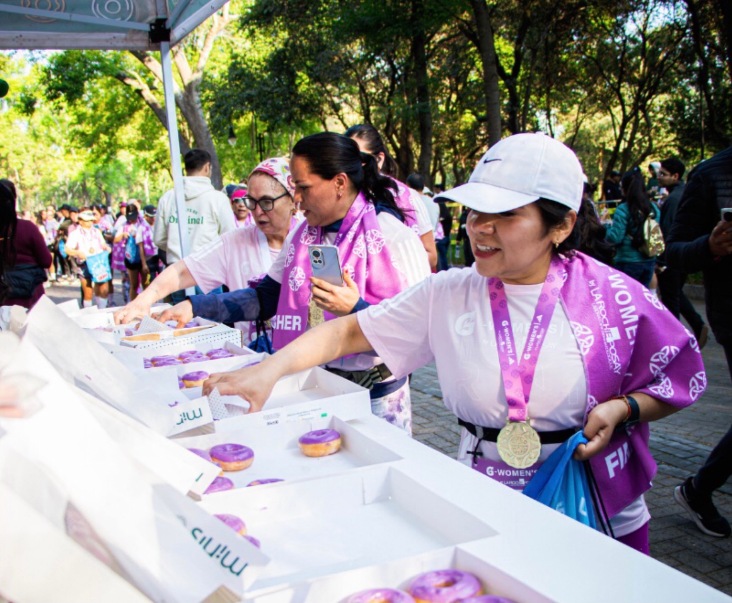 G-Women's Race — finishers recogiendo donas moradas en zona de activación