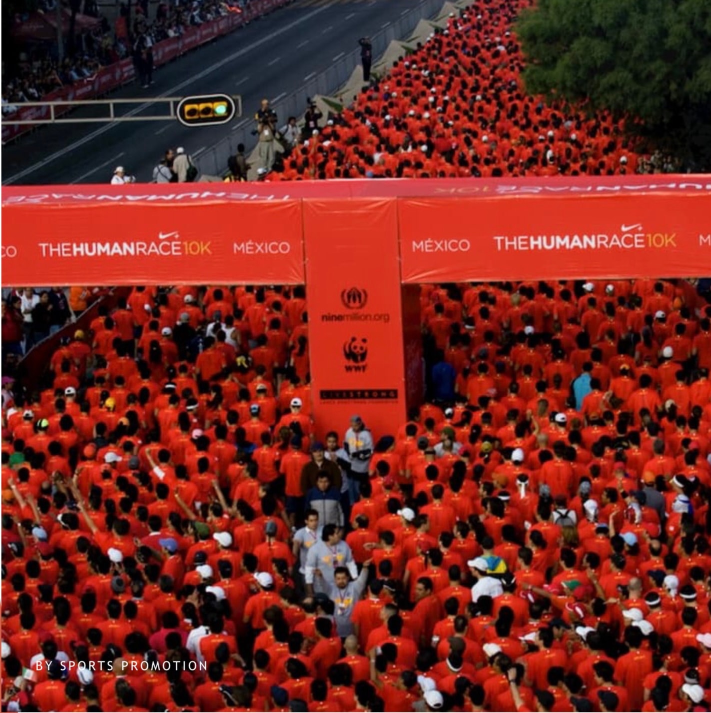 The Human Race Nike 10K Mexico — miles de corredores con playera roja bajo el arco de salida