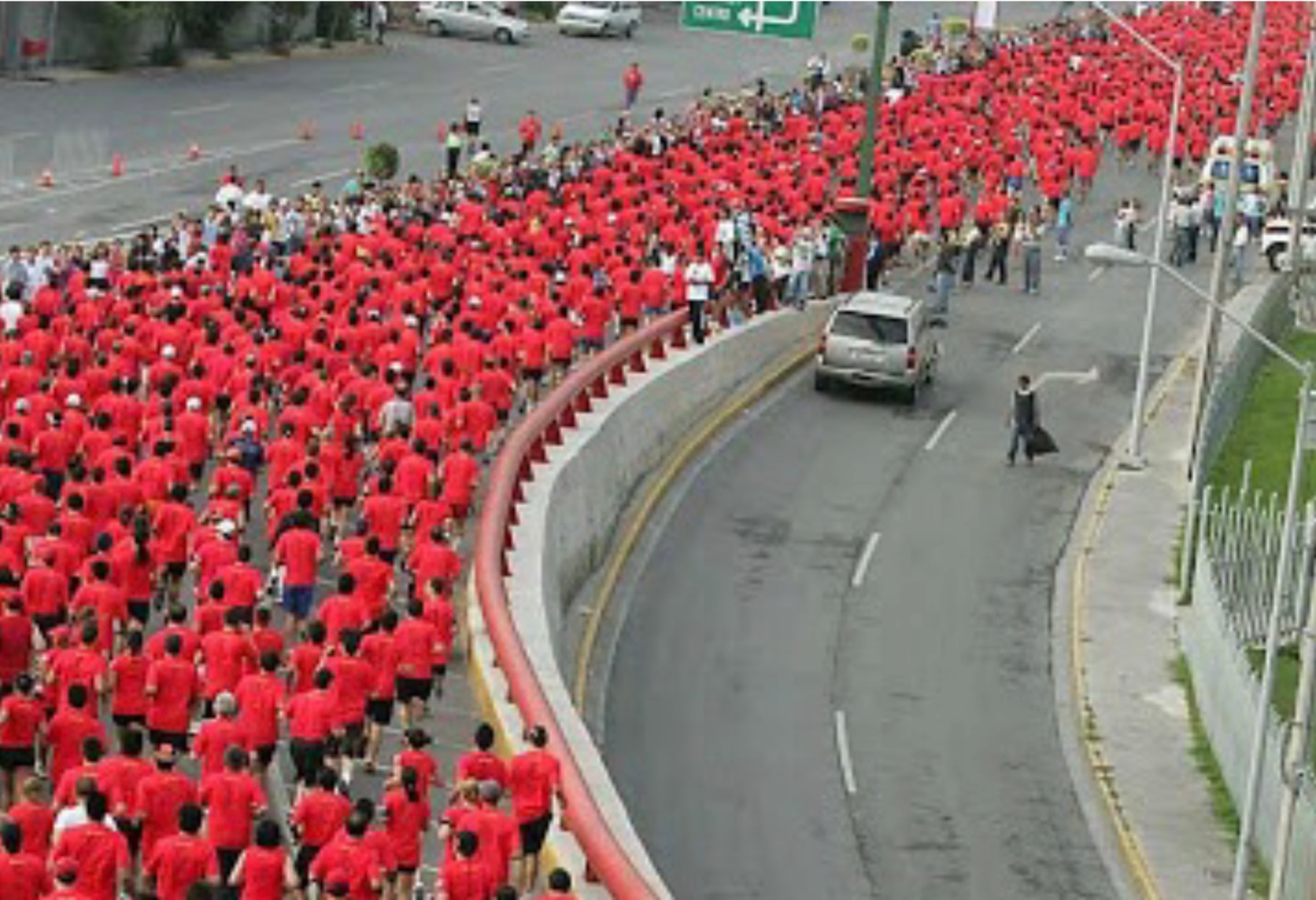 The Human Race Nike 10K — miles de corredores en camiseta roja sobre avenida