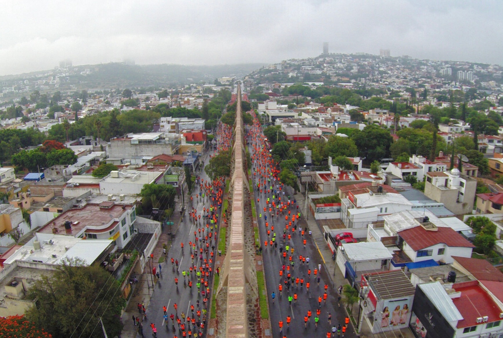 Querétaro Marathon — vista aérea de miles de corredores en naranja llenando la avenida principal